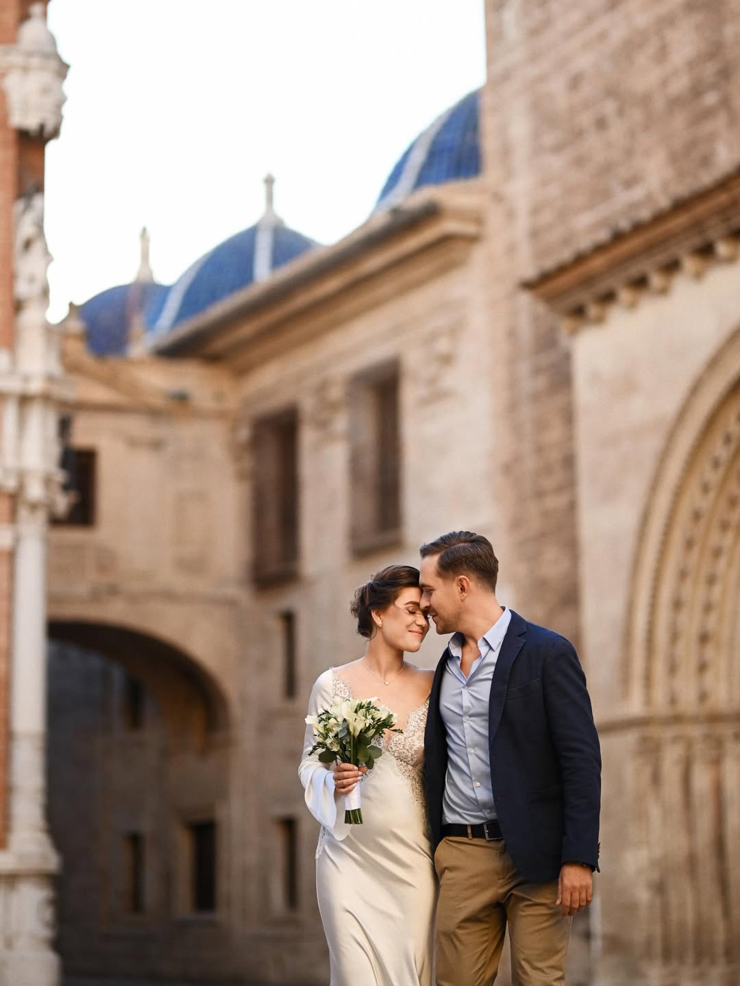 A joyful, candid moment of a bride and groom sharing a laugh near a vintage balcony in Valencia’s El Carmen district. Real emotions in a historic Mediterranean setting